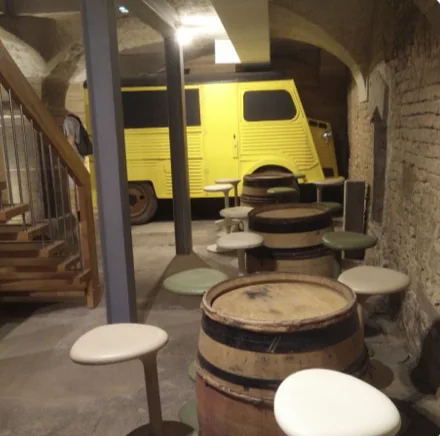 La cave voûtée en briques avec un fourgon jaune et des tonneaux
